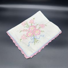 This vintage dresser scarf, handmade with a pink flower bouquet design, adds a quaint cottagecore touch to any room. Made from durable cotton, it features beautiful embroidery and lace detailing on three sides in soft pink and white hues.  * Handmade vintage dresser scarf * Features pink flower bouquet design * Embroidered detailing * Cottagecore aesthetic  * Made from durable cotton * Soft pink and white colors It has no rips or tears but, a few small stains. Condition: Pre-Owned  Please see the pictures for the full description. Pink Vintage Handkerchiefs With Floral Embroidery, Vintage Pink Floral Embroidered Handkerchiefs, Pink Embroidered Cotton Handkerchiefs, Spring Cotton Handkerchiefs With Floral Embroidery, Pink Cotton Handkerchief For Spring, Flower Bouquet Design, Pink Flower Bouquet, Dresser Scarf, Vintage Dresser