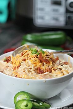 a white bowl filled with macaroni and cheese on top of a plate next to sliced jalapenos