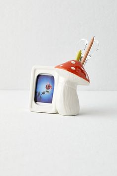 a small tv sitting on top of a mushroom shaped object with a toothbrush sticking out of it