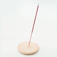 a red stick sticking out of the top of a round object on a white surface