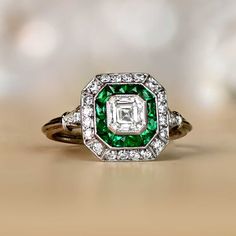 A Beautiful geometrically designed diamond engagement ring which features an Asscher-cut diamond surrounded by a double row of natural calibre-cut emeralds and full-cut diamonds. The total emerald weight is 0.50 and the total diamond weight including the row is 0.80. ✦ ENGAGEMENT RING SPECIFICATIONS: Diamond Cut: Asscher-cut Diamond Color: I Color Diamond Clarity: VS2 Clarity Carat Weight: 0.40 Carats Total Carat Weight: Approximately 0.80 Total Gram Weight: 4.6g ✦ WHAT COMES IN YOUR SHIPMENT: - Asscher Ring, Diamond And Emerald Ring, Estate Diamond Jewelry, Asscher Diamond, Asscher Cut Diamond, Geometric Ring, Double Halo, Asscher Cut, Geometric Diamond