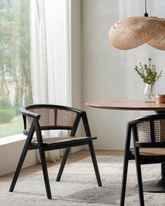 two chairs sitting next to each other in front of a table with a vase on it