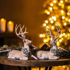 two deer figurines sitting on top of a table next to a christmas tree