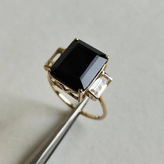 ITEM DESCRIPTION: >> The Ring is made from Solid 14K Yellow Gold. Gemstone used is absolutely natural and ethically sourced. >> Natural White Topaz and Black Onyx in prong setting is studded on it with utmost precision. >> This is a minimalist design which makes it a hassle free and everyday jewelry. >>Center Gem: Black Onyx Center Gem size: 12x10 mm Center Gem weight: 4.95 ct >>Side gemstone: White Topaz Side Gems size: 6x3 mm Gem weight: 1.05 carats Gold purity: 14K (58.33% approx.) Gold weigh Timeless Black Jewelry With Center Stone, Black Sapphire Ring In 14k Gold, 14k Gold Black Ring With Center Stone, Black 14k Gold Ring With Center Stone, Formal Black Sapphire Ring In 14k Gold, Black Emerald-cut 14k Gold Jewelry, 14k Gold Black Gemstone Rings, Black Onyx Jewelry, Onyx Jewelry