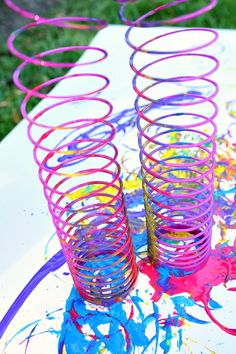 three colorful spirals sitting on top of a table covered in paint