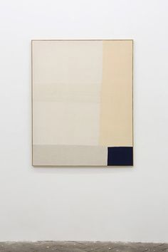 an abstract painting hangs on the wall in front of a white room with a bench