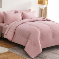 a bed with pink comforters and pillows in a room