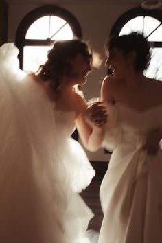 two women in white dresses are looking into each other's eyes as they stand together