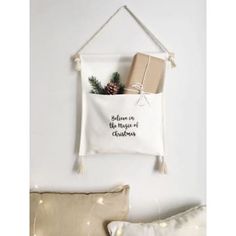 a christmas decoration hanging on the wall next to pillows and a pillow with a present in it