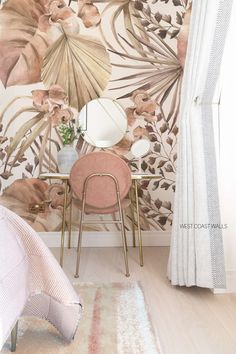 a chair and table in front of a wall with flowers on it, next to a mirror