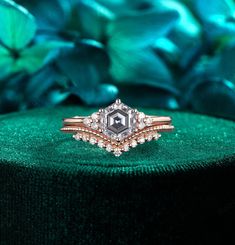 a diamond ring sitting on top of a green velvet covered box with flowers in the background