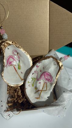 two pink flamingos are sitting inside of an open gift box on top of cardboard