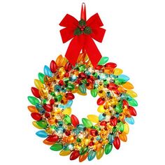 a christmas wreath with red bow hanging on a white wall, decorated with colorful glass beads