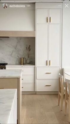 a kitchen with white cabinets and marble counter tops