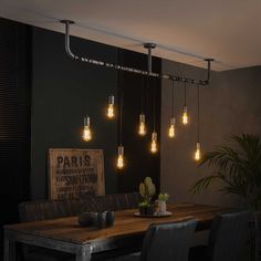 a dining room table that has some lights hanging from it