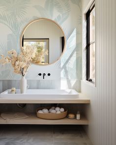 a white sink sitting under a round mirror next to a wall mounted faucet