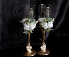 two wine glasses decorated with flowers and gold rimmed stemware are sitting side by side on a black background