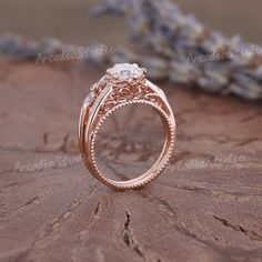 a rose gold engagement ring with an oval center stone and filigrees on the sides