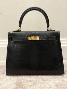 Gorgeous Hermes Lizard Kelly. In a timeless classic must have for any Hermes lover. Beautiful Skin and well taken care of.  Color - Black  Size - 25 Hardware - Gold Tone  Material - 100% Lizard, Togo Leather interior Made in - France  Condition - Pre-owned excellent, Has been refreshed at the leather SPA, Has slight hairline scratches on hardware. Has shoulder strap and Clochette, sadly no Lock or keys but easily replacable. See pics and video. Kelly 25, Elegant Dresses Classy, Togo Leather, Top Handle Bags, Hardware Gold, Fashion Wedding, Beautiful Skin, Leather Interior, Timeless Classic