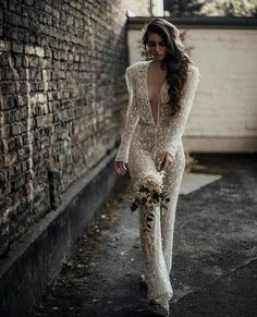 a woman is walking down the street in a wedding dress with long sleeves and open back