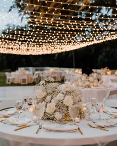 the table is set with white flowers, candles and place settings for dinner or reception