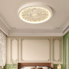 a large bed sitting under a ceiling light in a room with green walls and furniture