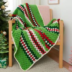 a green and red blanket sitting on top of a chair next to a christmas tree