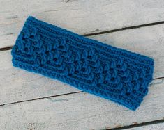 a blue crocheted headband laying on top of a wooden table