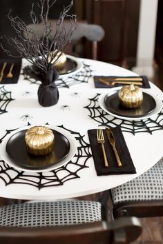 a white table topped with black and gold place settings