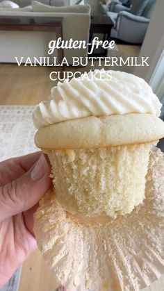 a hand holding a vanilla buttermik cupcake with frosting on top and the words gluten free vanilla buttermilk cupcakes above it