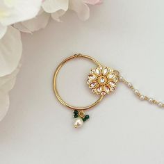 a close up of a flower on a chain with pearls and a bead around it