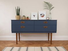 a blue dresser sitting on top of a hard wood floor next to a white wall