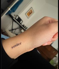 a person with a small tattoo on their wrist that says, sonder in cursive writing