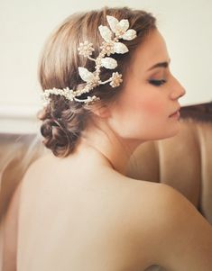 a woman wearing a bridal hair piece with flowers in it's hair is looking at her cell phone