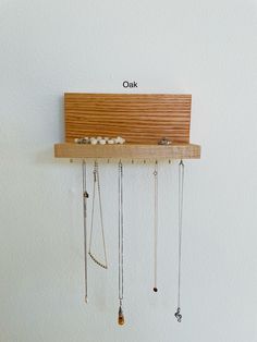 a wooden shelf with several necklaces hanging from it's sides and labeled oak