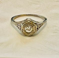 a close up of a ring with a diamond in the center on a white surface