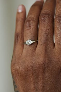 a close up of a person's hand with a diamond ring on their finger