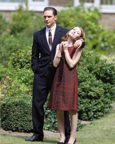 a man in a suit and tie standing next to a woman wearing a red dress