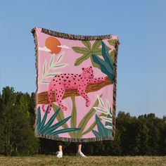 a woman standing in front of a pink and green blanket with a leopard on it