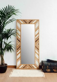 a mirror sitting on top of a wooden floor next to a potted palm tree