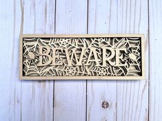 a wooden plaque with the word beware carved into it's sides on a white wood background