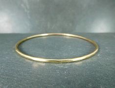 This beautiful and elegant 14K gold filled bangle bracelet has been hand formed, hammered and polished by me.   Please see sizing information below or in the second photo above. The bracelet is 2.06 mm and is made from 12 gauge wire. The bangle comes in 5 sizes: Extra Small 2.25 inches (5.7cm) inside diameter 7 inches (17.8cm) circumference Small 2.38 inches (6.0cm) inside diameter 7.5 inches (19.1cm) circumference Medium 2.5 inches (6.4cm) inside diameter 8 inches (20.3cm) circumference Large 2.75 inches (7cm) inside diameter 8.5 inches (21.6cm) circumference Extra Large 2.87 inches (7.3cm) inner diameter 9 inches circumference If you need a size other than one that is listed, please let me know, and I will customize the size for you. Custom sizes are not returnable. How to measure your h Gold Minimalist Hand Forged Bangle, Minimalist Hand Forged Gold Bangle, Minimalist Hammered Round Bangle, Everyday Gold Hammered Bangle, Hammered Yellow Gold Bangle For Everyday, Everyday Hammered Yellow Gold Bangle, 14k Gold Hammered Bangle As Gift, Hammered 14k Gold Bangle Gift, Field Notes Wallet