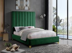 a bed with green headboard and foot board in a room next to a window