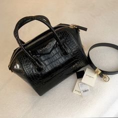 Featuring The Signature Trapezoidal Silhouette And Pentagonal Givenchy Patch, This Handbag Is A Part Of The Antigona Collection And Is Crafted From Glossy Crocodile-Embossed Leather. It Is Fitted With A Top Carry Handle And Detachable Shoulder Strap For Versatile Wear. Condition:Excellent Accessories: Includes Removable Leather Strap. Detailed Pictures And Provide An Overall Rating To Help In Describing The Condition Of This Item. Designer Givenchy Made In Italy Size (In) 11 (Width) X 9.5 (Height) X 6.5 (Depth) Handle/Strap Rounded Leather Handles; Detachable Leather Strap Handle/Strap Drop (In) 4 (Handles); 14 (Strap) Exterior Material Black Calfskin Leather Luxury Crossbody Bag With Crocodile Pattern, Luxury Crocodile Pattern Crossbody Bag, Luxury Crocodile Pattern Shoulder Bag, Luxury Evening Bag With Crocodile Pattern, Luxury Crocodile Pattern Shoulder Bag For Formal Occasions, Luxury Crocodile Pattern Shoulder Bag For Formal Events, Elegant Evening Shoulder Bag With Crocodile Pattern, Evening Leather Bag With Crocodile Pattern, Designer Crocodile Pattern Shoulder Bag For Evening