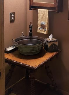 a bathroom sink sitting on top of a wooden table in front of a framed mirror