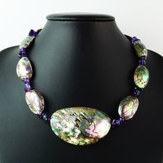 Discover the captivating beauty of this Paua Shell choker necklace, also known as Abalone, featuring stunning accents of tumbled Purple Amethyst and faceted Teal Apatite. The Paua Shell's mesmerizing, multi-colored hues—ranging from blue, teal, and green to pink, gray, purple, and black—create a swirling design that is unique to each shell. The center focal piece measures an impressive 57x35mm, while the surrounding shell beads are 27x18mm, making this 17.25-inch necklace a true statement piece. British Crown Jewels, Vintage Jewelry Ideas, Shell Choker, Artisan Bracelets, Vintage Beads Necklace, Paua Shell, Unusual Jewelry, February Birth Stone, Blue Teal