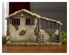 a small house made out of rocks and grass on a wooden table in front of a window