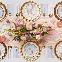 an overhead view of a table with plates, flowers and gold trimmings on it