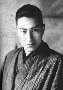 an old black and white photo of a man in kimono looking at the camera