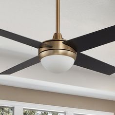 a ceiling fan with a light on top of it in a room next to windows